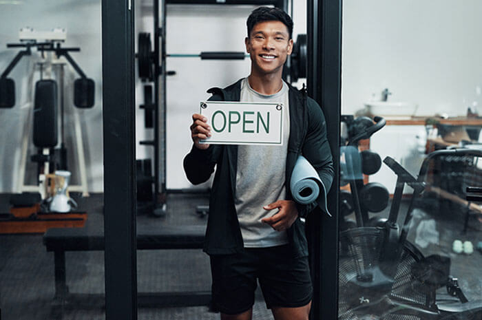 gym owner holding open sign